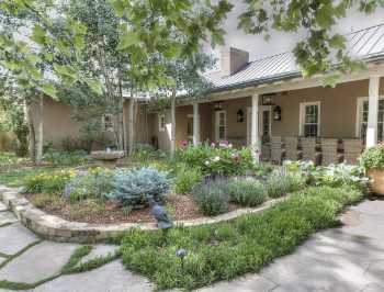 Courtyard Area Landscape Design Prosper Texas residence with stone masonry landscape border, flagstone walkway and Texas native plants in backyard outdoor living area.