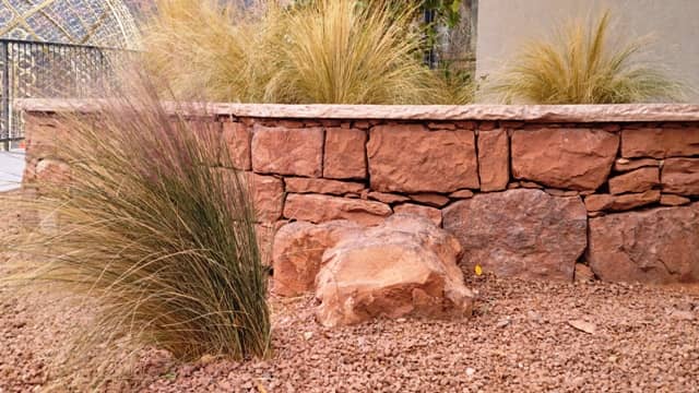 Natural stone elevated planter beds with tall landscaping grasses